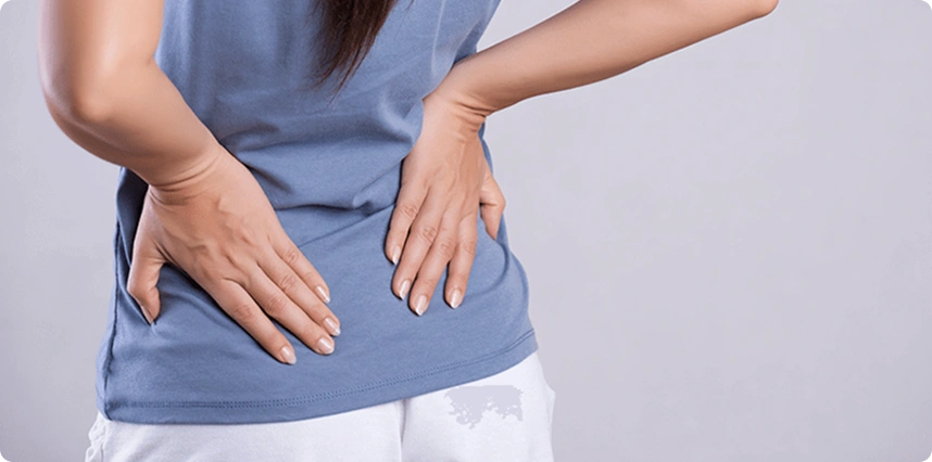 Person experiencing lower back pain, holding the lumbar region.